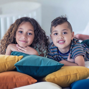 Two children lying on bed or floor  with colorful pillows
