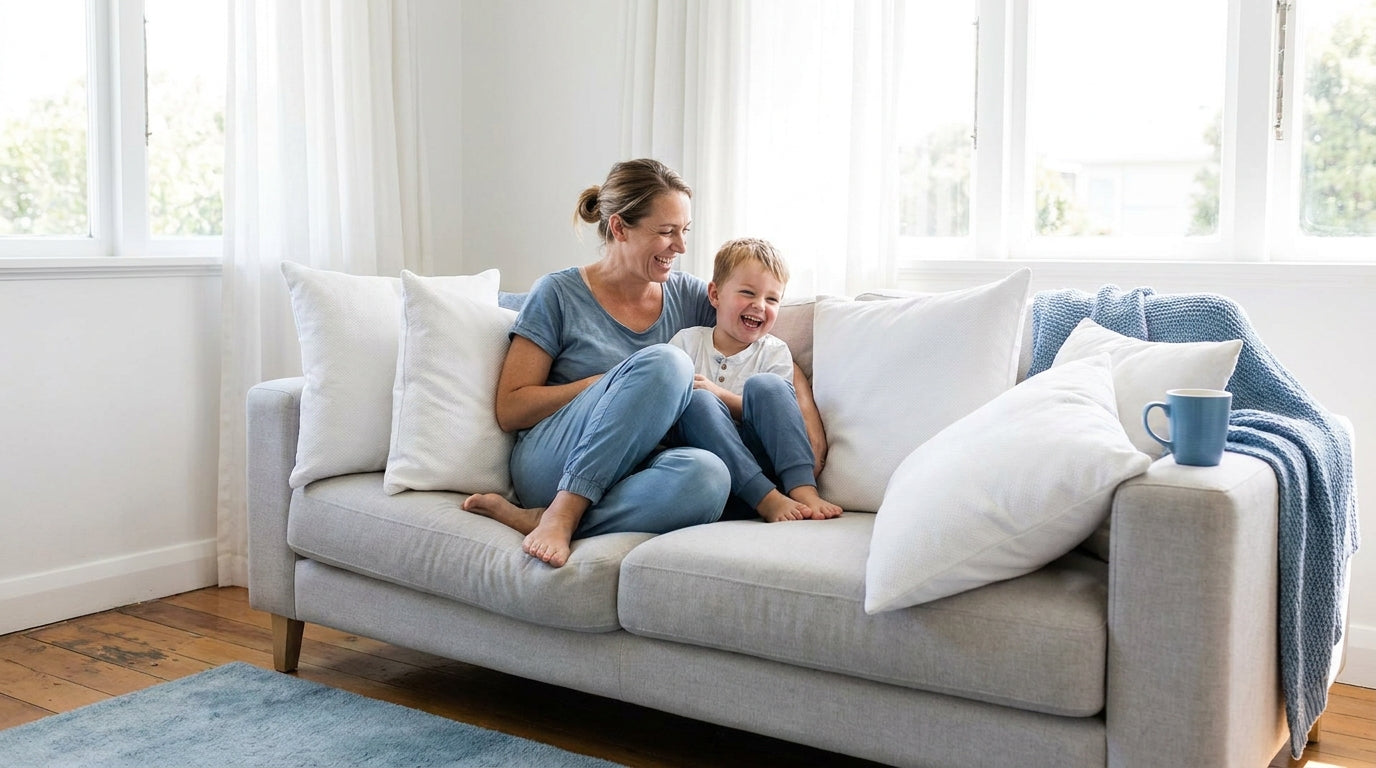 Parent and child laughing on a couch with white MiteGuard cushion covers